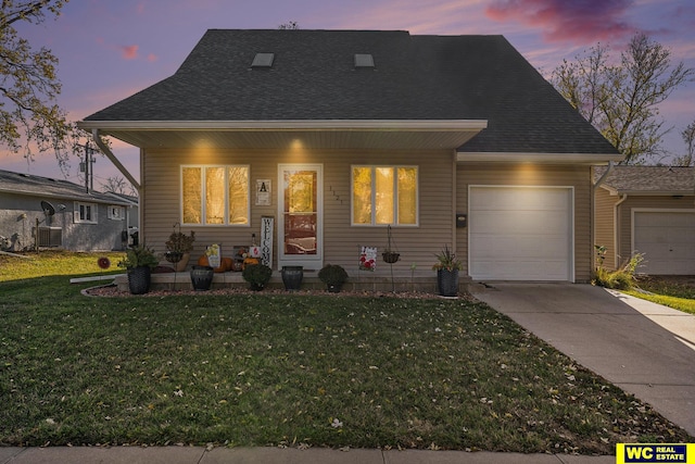 view of front facade with a garage, a lawn, and covered porch