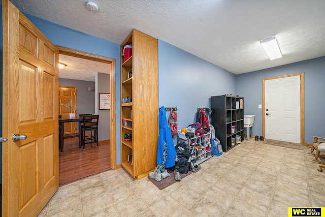 playroom with a textured ceiling and light wood-type flooring