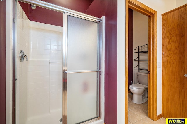 bathroom featuring a shower with shower door, tile patterned flooring, and toilet