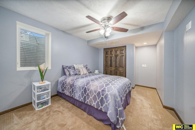 bedroom with a textured ceiling, light colored carpet, ceiling fan, and a closet