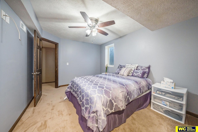 bedroom featuring a textured ceiling, light colored carpet, and ceiling fan