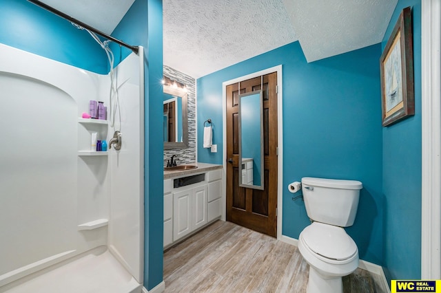 bathroom featuring walk in shower, vanity, a textured ceiling, hardwood / wood-style flooring, and toilet