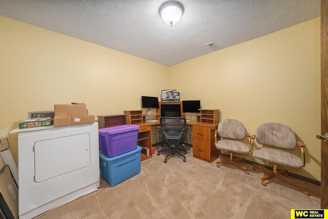 home office with light carpet, a textured ceiling, and washer / dryer