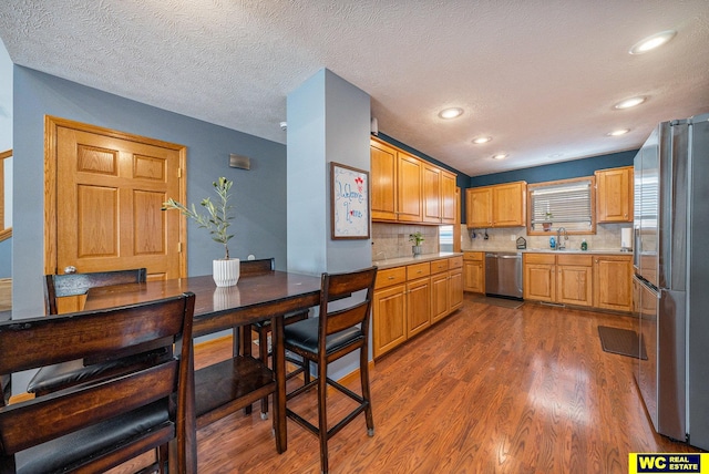 kitchen with tasteful backsplash, appliances with stainless steel finishes, a textured ceiling, dark hardwood / wood-style flooring, and sink