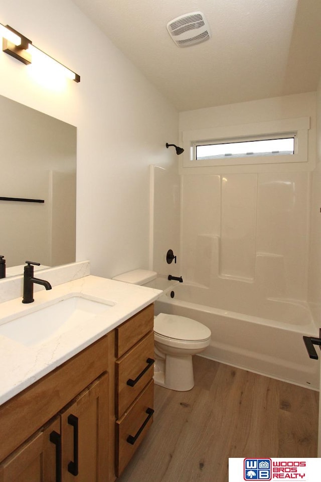 full bathroom with vanity, hardwood / wood-style flooring, toilet, and shower / bathtub combination