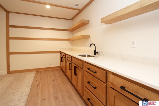 kitchen with light hardwood / wood-style floors, sink, and light stone counters