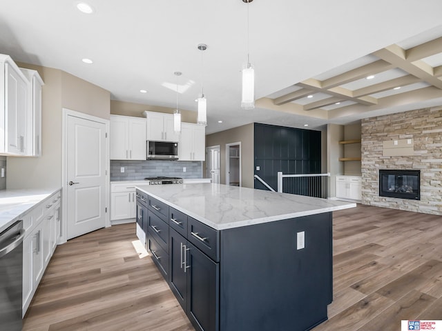 kitchen featuring a kitchen island, appliances with stainless steel finishes, decorative light fixtures, hardwood / wood-style flooring, and white cabinets