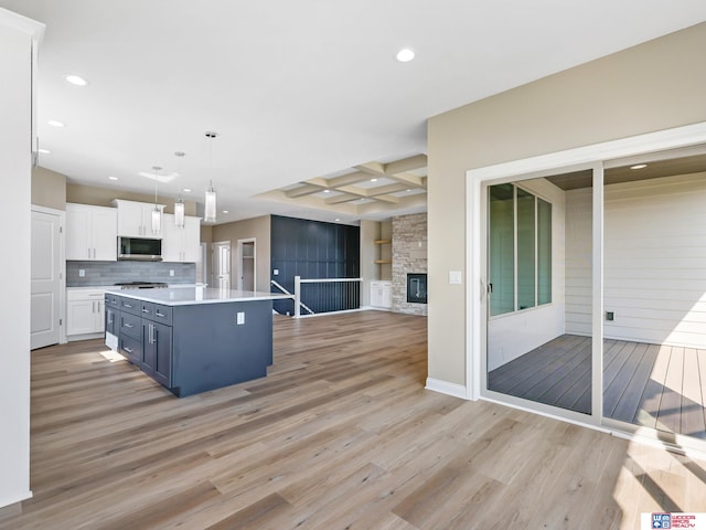 kitchen featuring white cabinets, stainless steel appliances, hanging light fixtures, and light hardwood / wood-style flooring