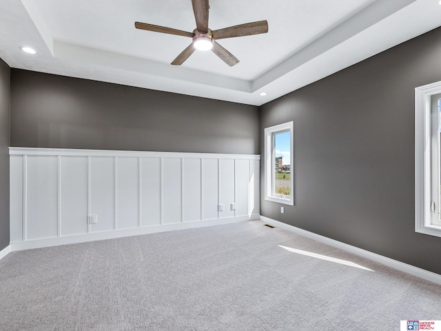 spare room featuring light colored carpet, ceiling fan, and a tray ceiling