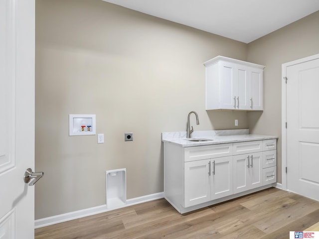 clothes washing area featuring light hardwood / wood-style floors, electric dryer hookup, cabinets, sink, and washer hookup