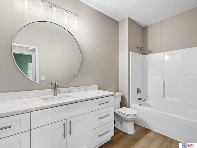 full bathroom featuring wood-type flooring, vanity, a textured ceiling, shower / tub combination, and toilet