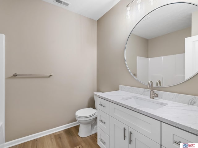 bathroom featuring vanity, hardwood / wood-style flooring, toilet, and a shower