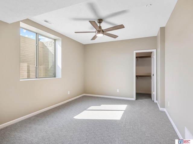 unfurnished bedroom with carpet flooring, ceiling fan, a walk in closet, and a closet