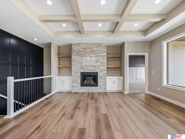 unfurnished living room featuring a fireplace, light hardwood / wood-style floors, beam ceiling, and coffered ceiling