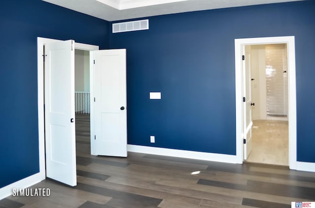 unfurnished bedroom featuring dark hardwood / wood-style floors and ensuite bath