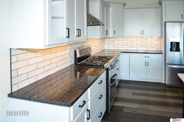 kitchen with appliances with stainless steel finishes, dark stone countertops, backsplash, white cabinets, and dark wood-type flooring