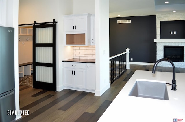 kitchen featuring white cabinetry, sink, a barn door, stainless steel fridge, and dark hardwood / wood-style flooring