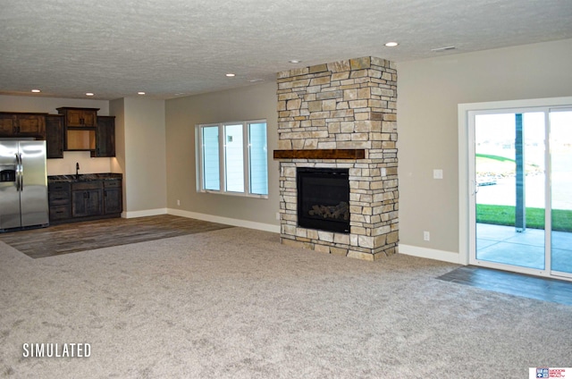 unfurnished living room with a fireplace, a textured ceiling, and carpet floors