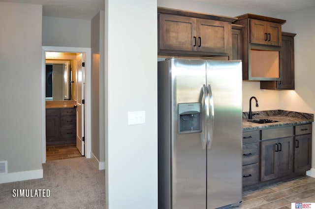 kitchen with dark stone countertops, sink, stainless steel fridge with ice dispenser, and light colored carpet