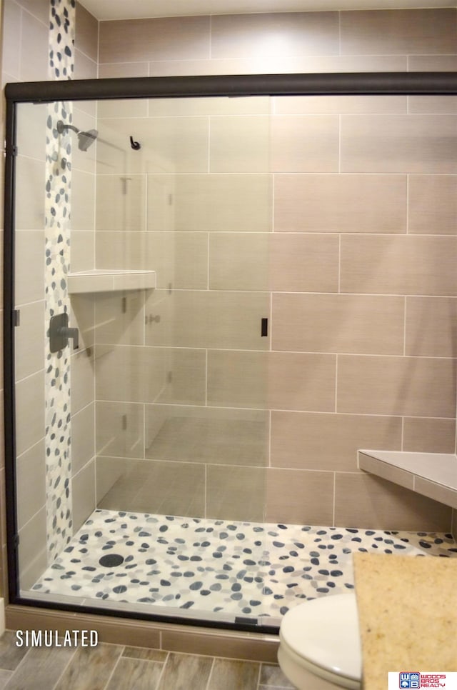 bathroom with toilet and a shower with door