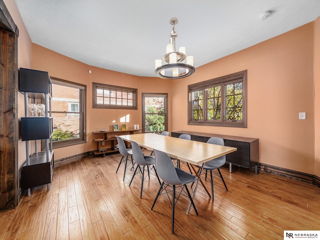 dining area with light wood-type flooring and a notable chandelier