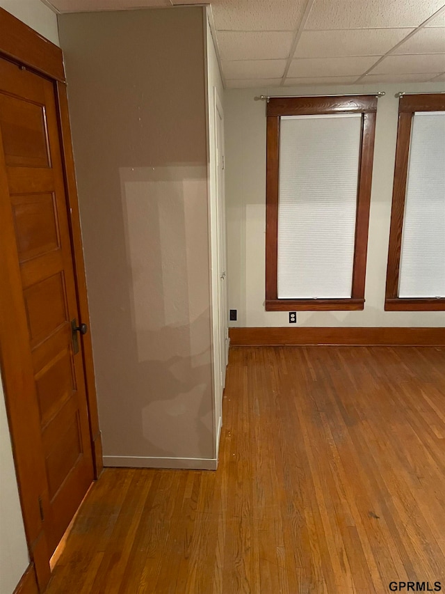 hallway with a paneled ceiling and light wood-type flooring