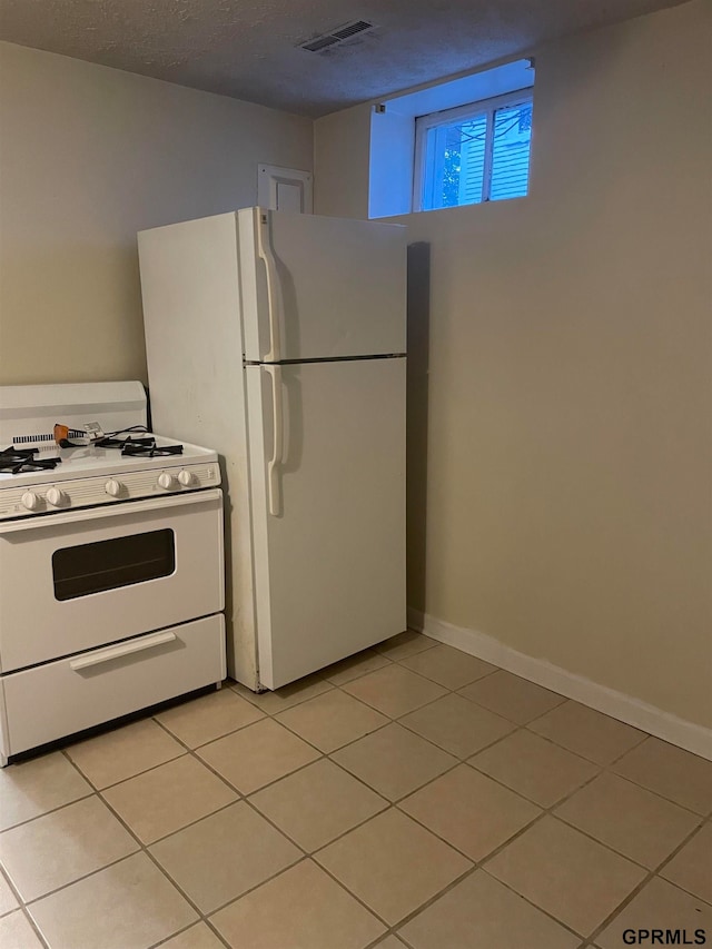 kitchen featuring a textured ceiling, light tile patterned floors, and white appliances