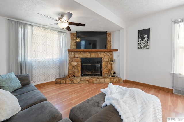 living room with a wealth of natural light, a fireplace, a textured ceiling, and hardwood / wood-style flooring