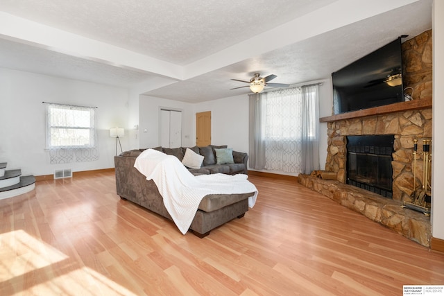 living room featuring a fireplace, ceiling fan, hardwood / wood-style floors, and a textured ceiling