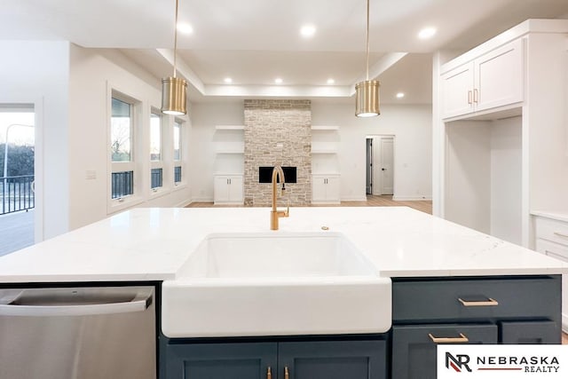 kitchen featuring decorative light fixtures, white cabinetry, light stone countertops, and stainless steel dishwasher