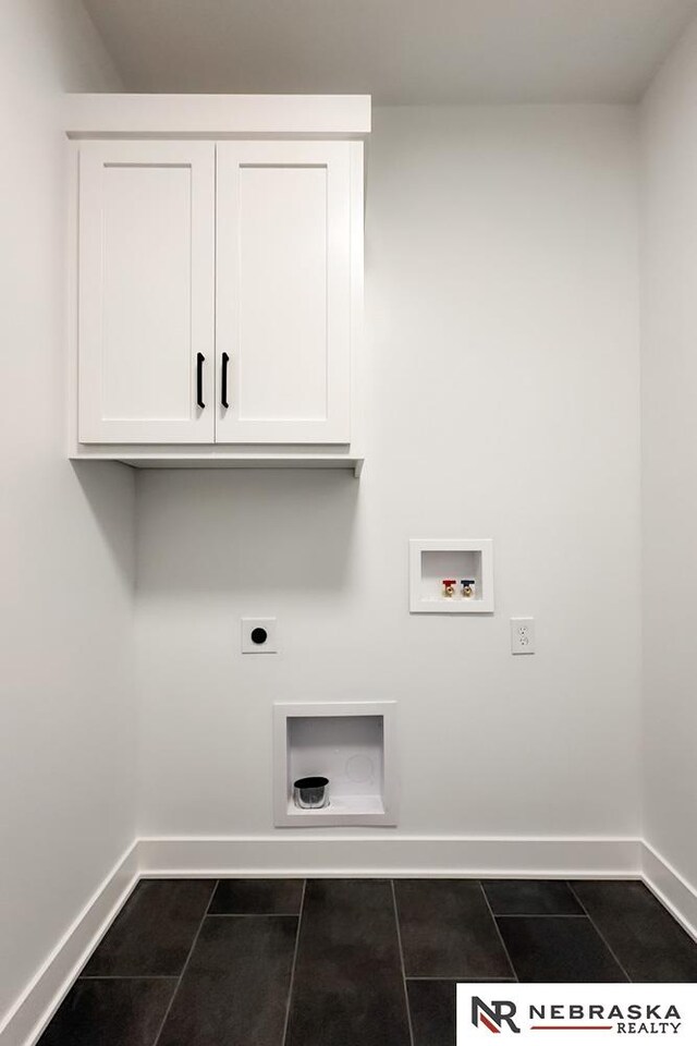 clothes washing area with washer hookup, cabinets, dark tile patterned flooring, and hookup for an electric dryer