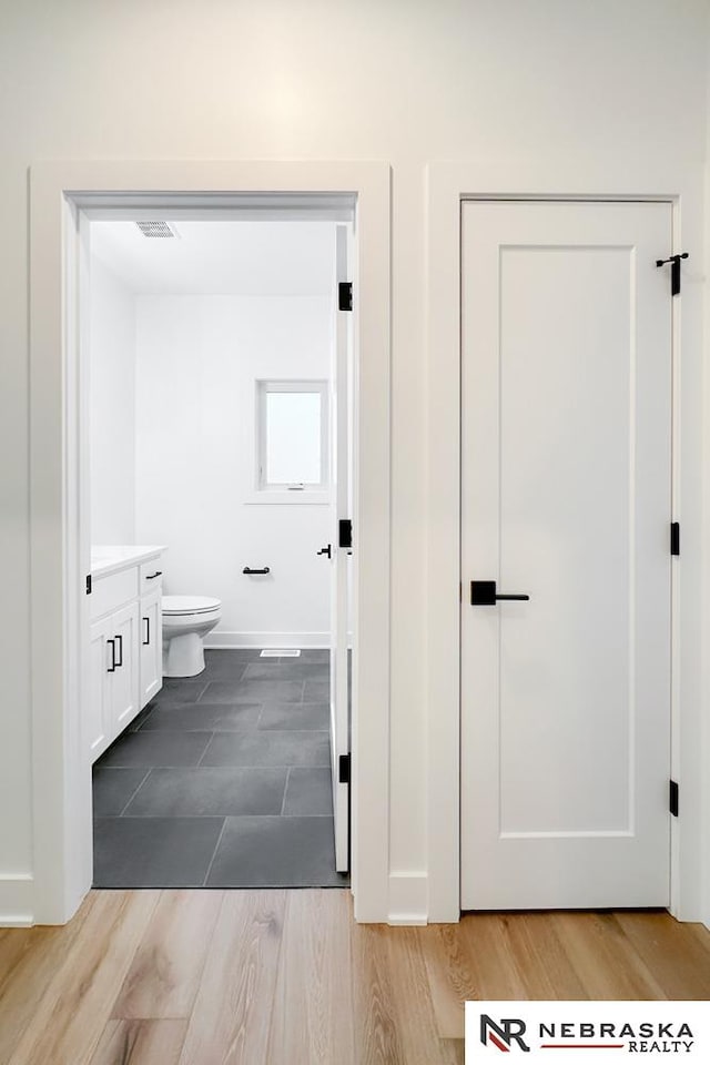 bathroom with vanity, wood-type flooring, and toilet