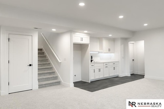 kitchen with sink, white cabinets, and dark colored carpet