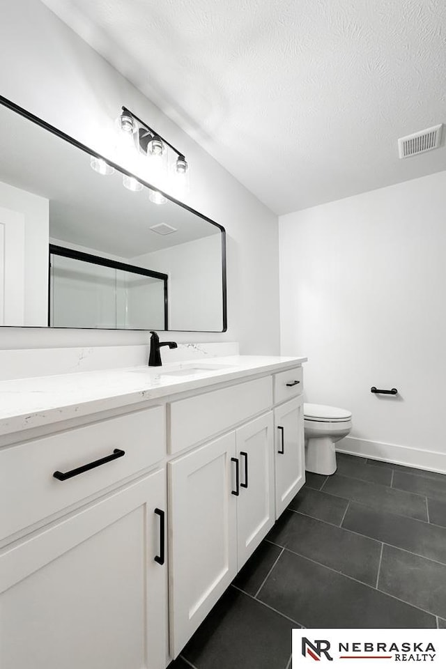 bathroom with toilet, a textured ceiling, vanity, and tile patterned floors