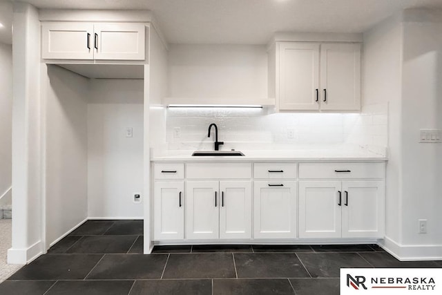 kitchen featuring tasteful backsplash, sink, white cabinets, and dark tile patterned floors