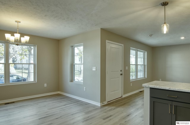 interior space with a chandelier, pendant lighting, light wood-type flooring, and plenty of natural light