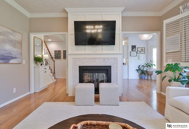 living room with crown molding, a tiled fireplace, and light wood-type flooring