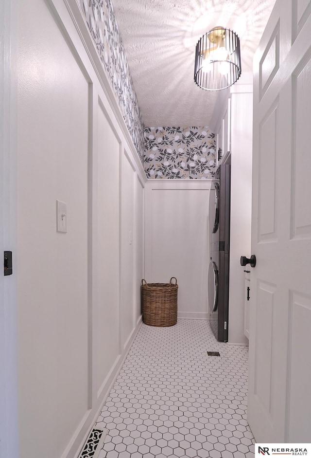 bathroom featuring a textured ceiling, tile patterned floors, and stacked washer and clothes dryer