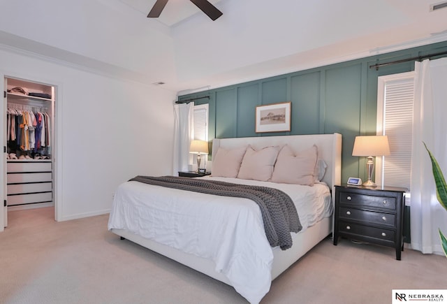 bedroom featuring a spacious closet, a closet, ceiling fan, and light carpet