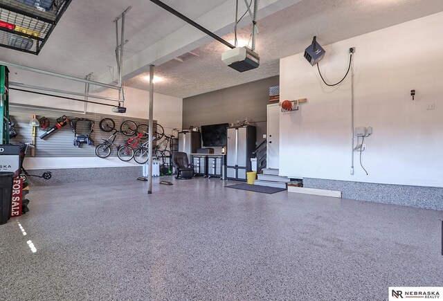 garage with stainless steel fridge and a garage door opener