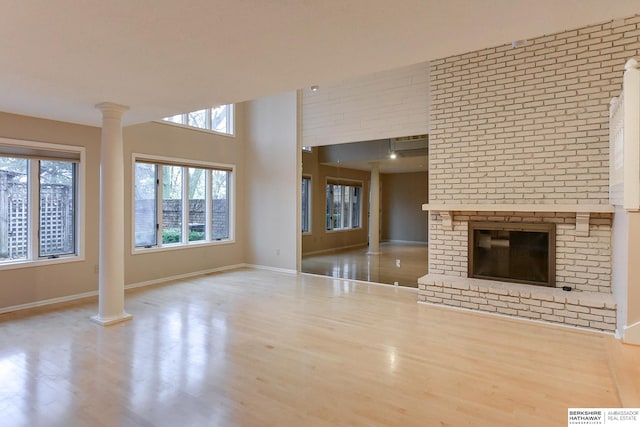 unfurnished living room featuring ornate columns, a high ceiling, and light hardwood / wood-style flooring