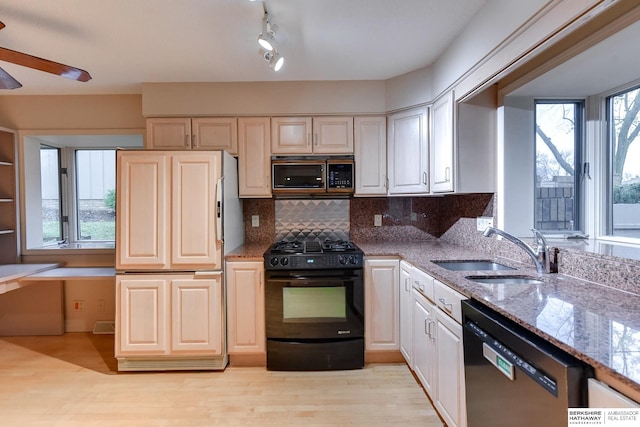 kitchen featuring sink, decorative backsplash, light hardwood / wood-style floors, black appliances, and light stone countertops