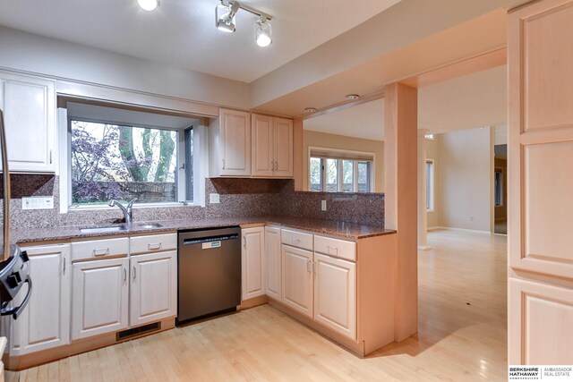 kitchen with black dishwasher, dark stone countertops, sink, backsplash, and light hardwood / wood-style flooring