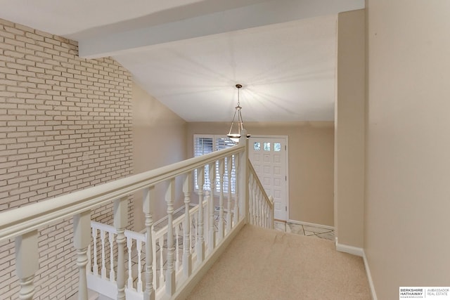 corridor featuring lofted ceiling with beams, brick wall, and light carpet