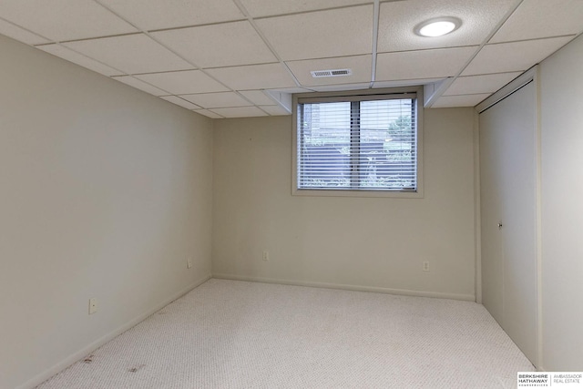 carpeted spare room with a drop ceiling