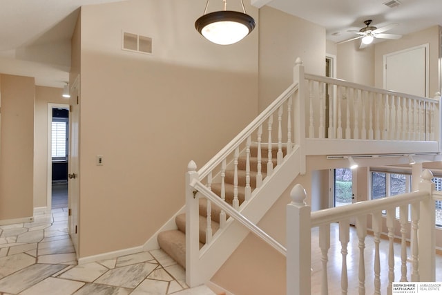 stairs with ceiling fan and a high ceiling