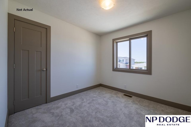 spare room with a textured ceiling and carpet floors