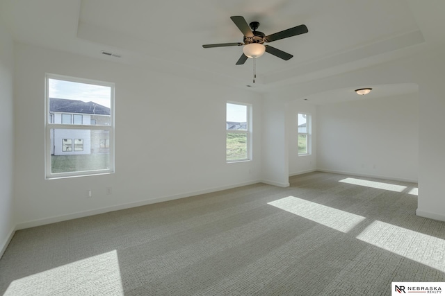 carpeted spare room featuring ceiling fan and a tray ceiling