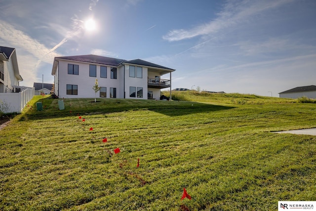 back of property featuring a balcony and a lawn