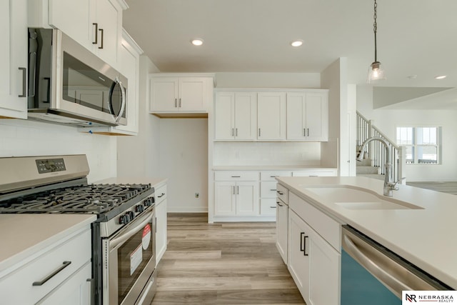 kitchen featuring pendant lighting, white cabinets, and appliances with stainless steel finishes